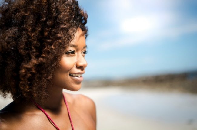 Close-up of thoughtful woman smiling at beach