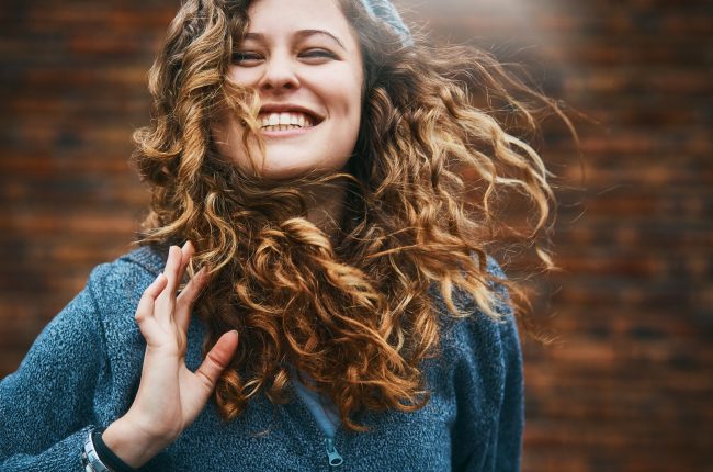 Beautiful girl with winter windblown hair laughs